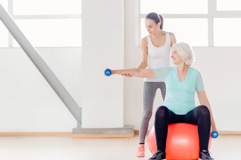 Cheerful elderly woman sitting on the fitness ball